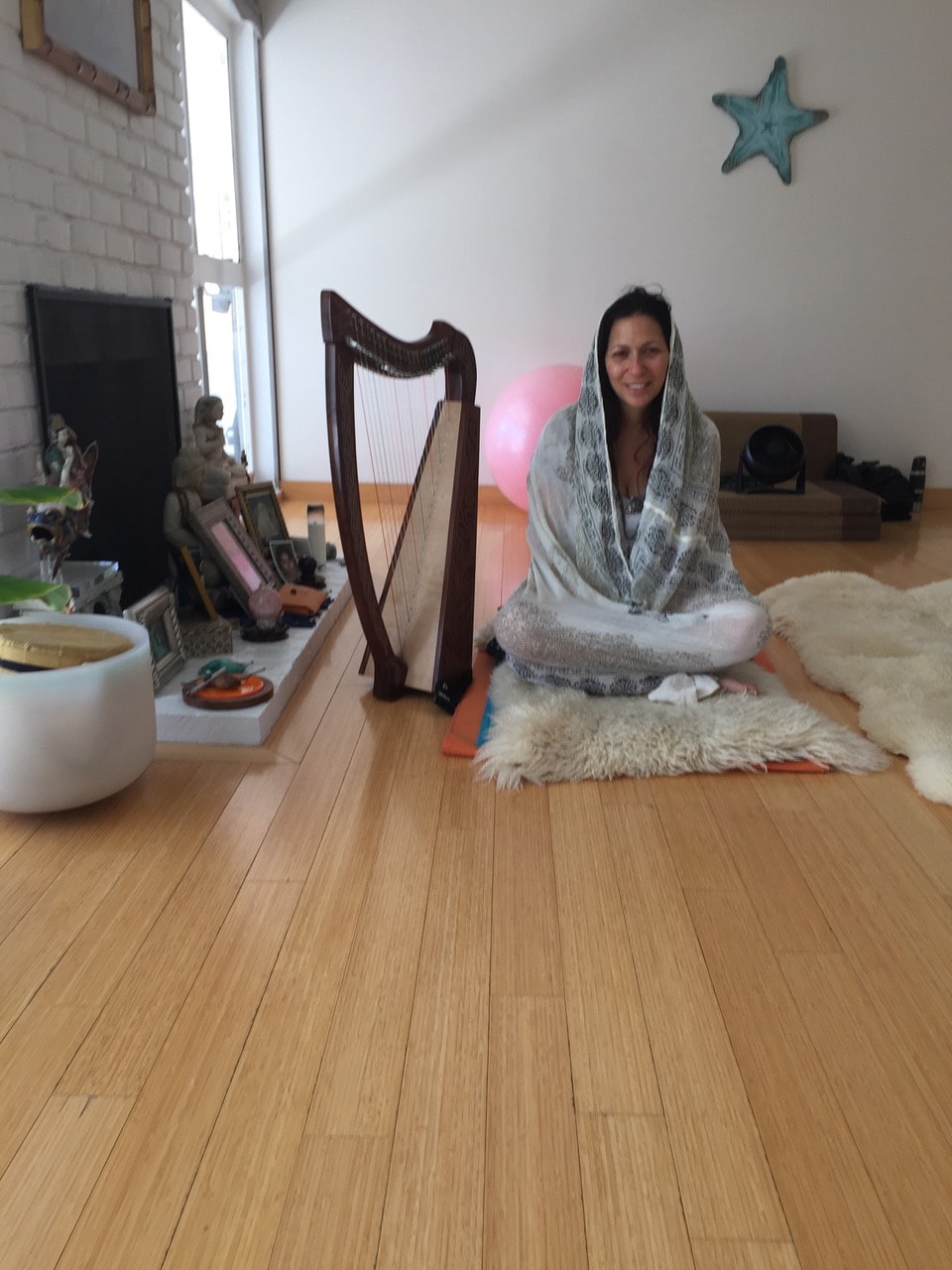 A woman seated beside a harp in the yoga studio